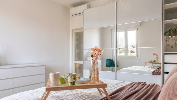 A modern bedroom with a large bed, a bedside table with a tray, a mirror, and a green chair. - Sardinia Re - Emerald House (Sassari)
