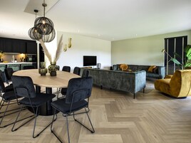 Una sala de estar moderna con una mesa redonda de comedor, sillas negras, un sofá gris y un sillón amarillo.