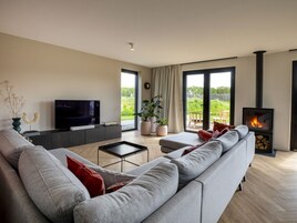 Una sala de estar moderna con un sofá gris, un televisor de pantalla plana, una mesita de centro y una chimenea.