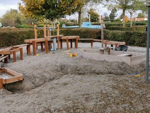 A sandy outdoor area with wooden structures, possibly a playground or construction site.