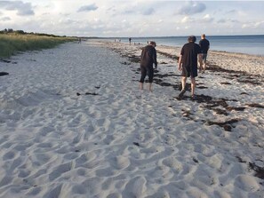 A sandy beach with people walking. - 6 Person Holiday Home in Idestrup (Idestrup)