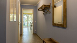 Ein Flur mit einer hölzernen Bank, einem Spiegel und einer Tür, die auf einen Balkon führt.