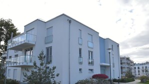 Ein modernes, mehrgeschossiges Wohngebäude mit Balkonen, einem gepflasterten Weg und einem angelegten Garten.