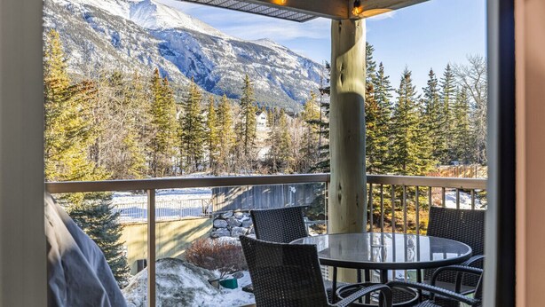 A balcony with a view of snow-covered mountains and trees.