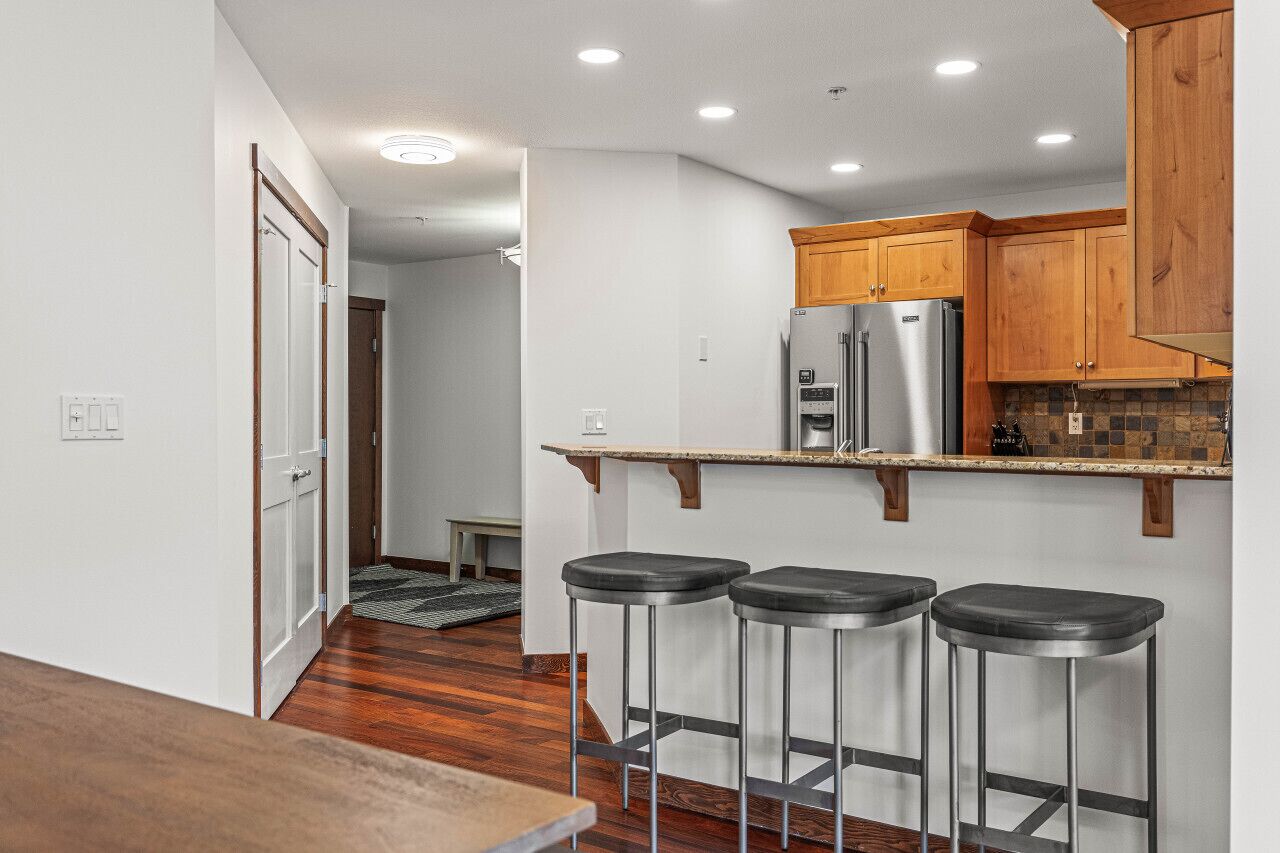 A modern kitchen with wooden cabinets, stainless steel appliances, and a bar stool seating area.