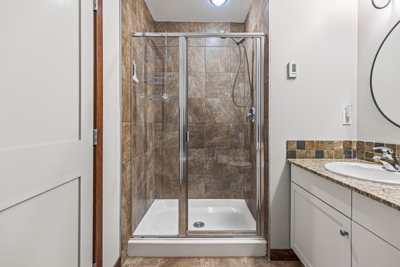 Ein modernes Badezimmer mit einer gläsernen Dusche, einem Waschbecken und einem Waschtisch mit Schränken.