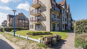 A modern apartment building with multiple balconies, a paved walkway, and well-maintained landscaping. - Apartment Near Koksijde by the Sea (Koksijde)