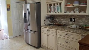 A kitchen with a stainless steel refrigerator, white cabinets, and a tiled backsplash. - SUMMER FUN IN A 3BED/2BATH SINGLE FAMILY HOME! (Belmar)