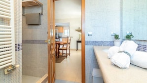Une salle de bain avec douche, toilettes et lavabo, ainsi qu’un coin repas avec une table et des chaises.