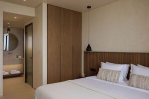 A hotel room with a bed, a wooden headboard, a bedside table, a mirror, and a hanging pendant light.