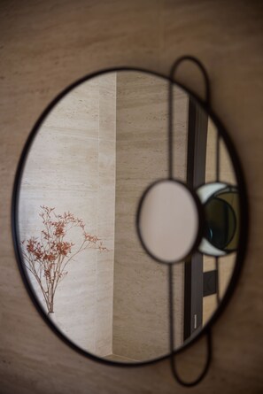 Un miroir rond reflétant une pièce dans laquelle on aperçoit une plante et une porte.
