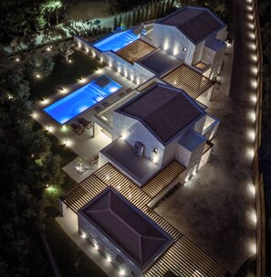 Une maison moderne dotée d’une piscine, de plusieurs terrasses et d’un éclairage extérieur.