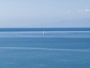 Une mer calme, avec un seul voilier à l'horizon.