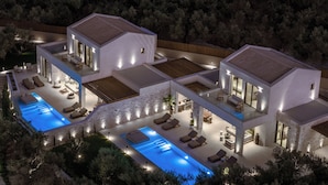 Una casa moderna con piscina, varias zonas de estar al aire libre y un patio bien iluminado.