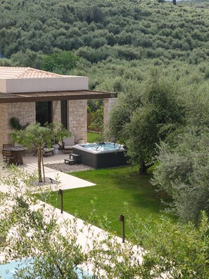 Una casa moderna con fachada de piedra, jacuzzi y un patio amueblado.