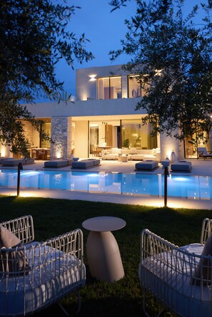 A modern outdoor pool area with lounge chairs and a dining area.