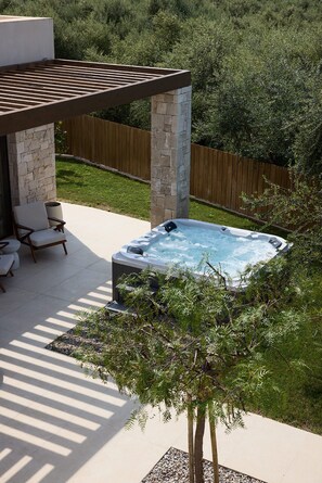 A hot tub in a backyard with a stone wall, a wooden pergola, and a chair. - Valerozo Villa Maestosa - Pool, Jacuzzi & steps to the beach (Ionian Islands, Zakynthos)