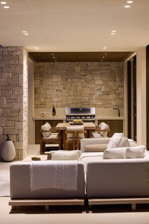 A modern interior with a stone wall, a dining area, and a sofa.