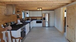 Una cocina moderna con paredes de madera, electrodomésticos de acero inoxidable y encimera negra.