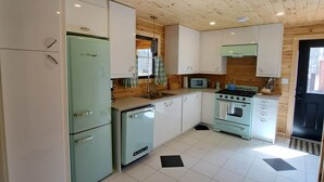 Een keuken met witte kastjes, een groene koelkast, een fornuis en een magnetron.