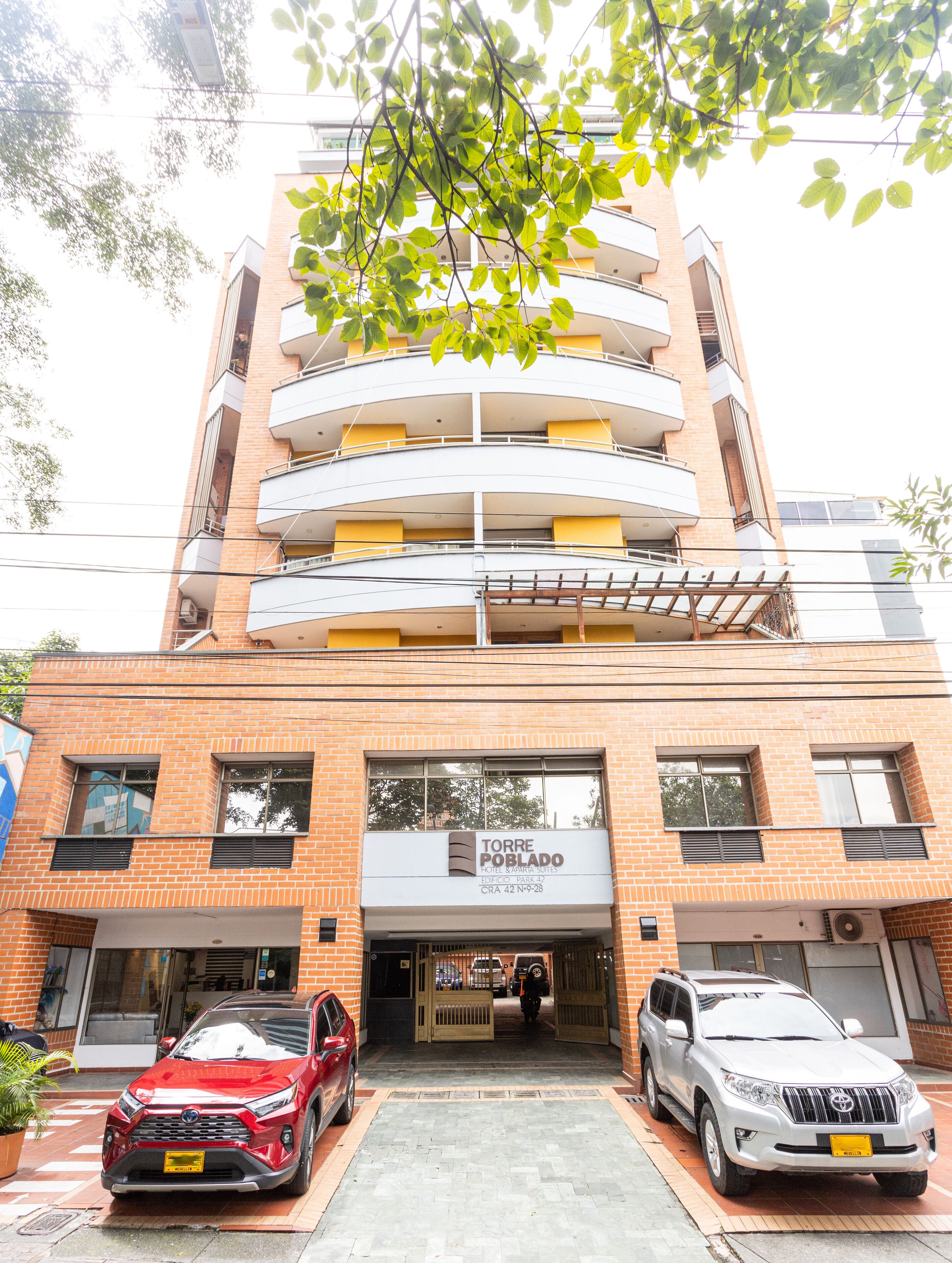 A multi-story hotel with a brick facade, balconies, and a sign indicating it is the Torre Poblado Hotel.