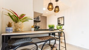 Une cuisine moderne dotée d’un îlot central, d’un four à micro-ondes et d’un évier. L’îlot est agrémenté de plantes en pot, et un luminaire suspendu se trouve au-dessus.