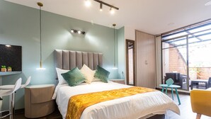 Une chambre à coucher moderne avec un grand lit, une table de chevet, une chaise et une vue sur l’extérieur.