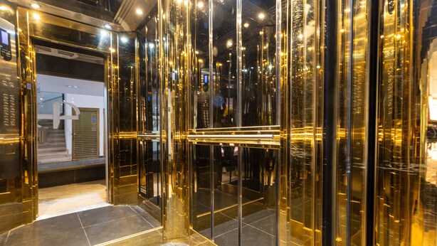 Un ascenseur moderne doté de portes en verre réfléchissant et d’un intérieur métallique.