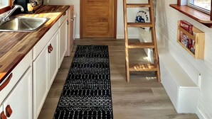 A compact kitchen with a loft bedroom, wooden ceiling, and a ladder for access. - Tiny House - Big Fun! (Zanesfield)