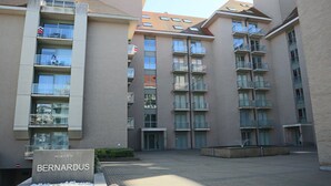 A multi-story residential building with balconies, a sign reading "RESIDENCE BERNARDUS," and a paved courtyard. - Apartment in Nieuwpoort Near the Beach (Nieuwpoort)
