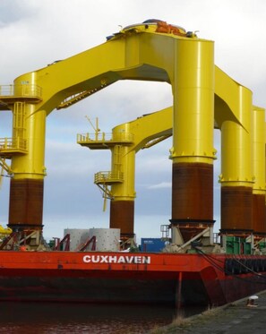 Una gran estructura industrial amarilla con un barco rojo llamado CUXHAVEN amarrado abajo.