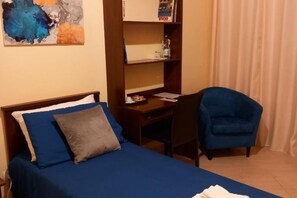 Une chambre à coucher avec un lit, un bureau, une chaise et une bibliothèque.