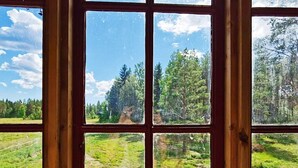 Une fenêtre donnant sur une forêt et un ciel dégagé.