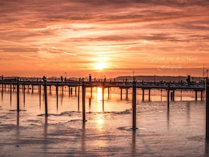 Une jetée s’avançant dans une étendue d’eau au coucher du soleil.