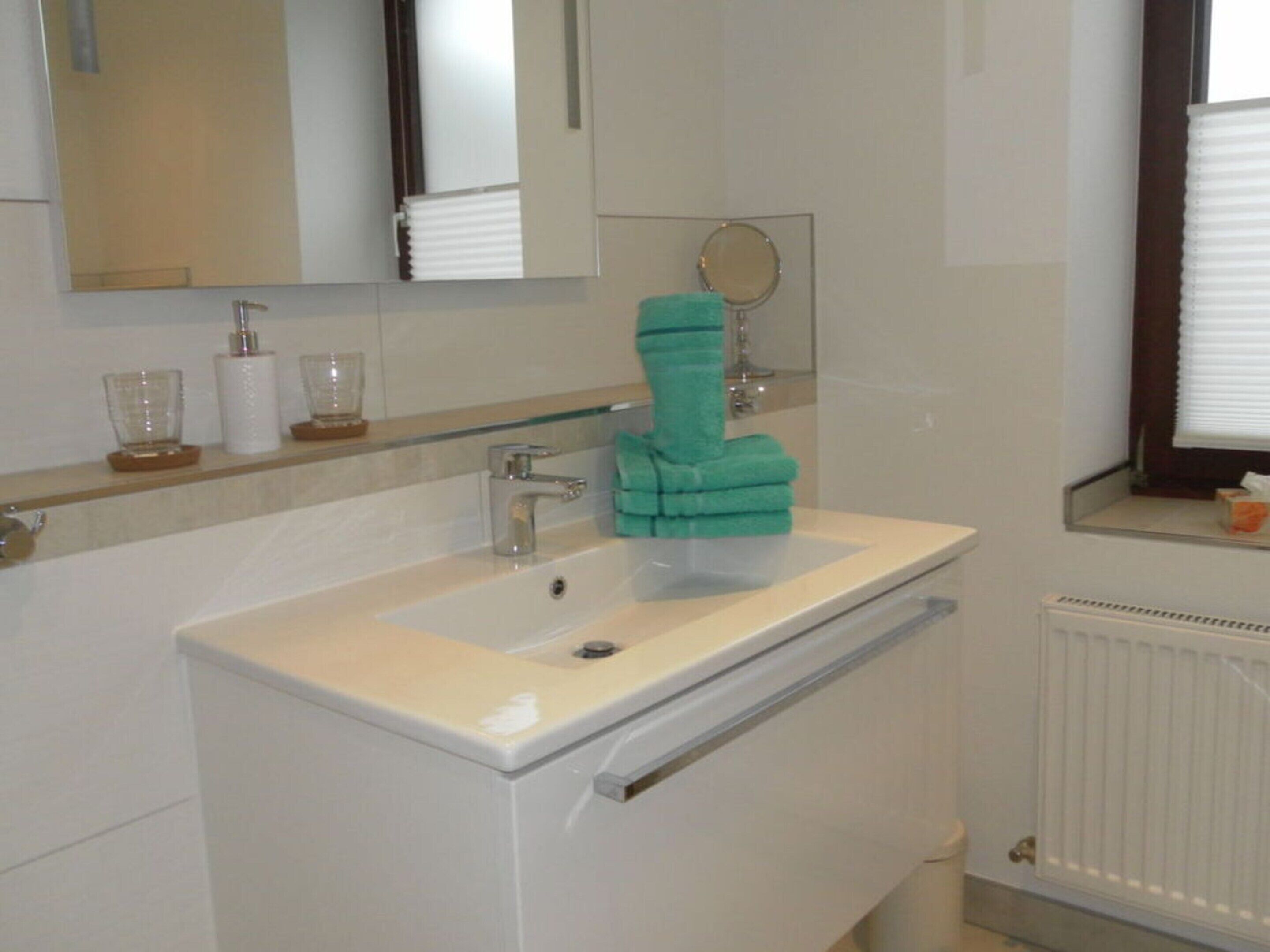 A bathroom with a white sink, a mirror, and a towel rack.