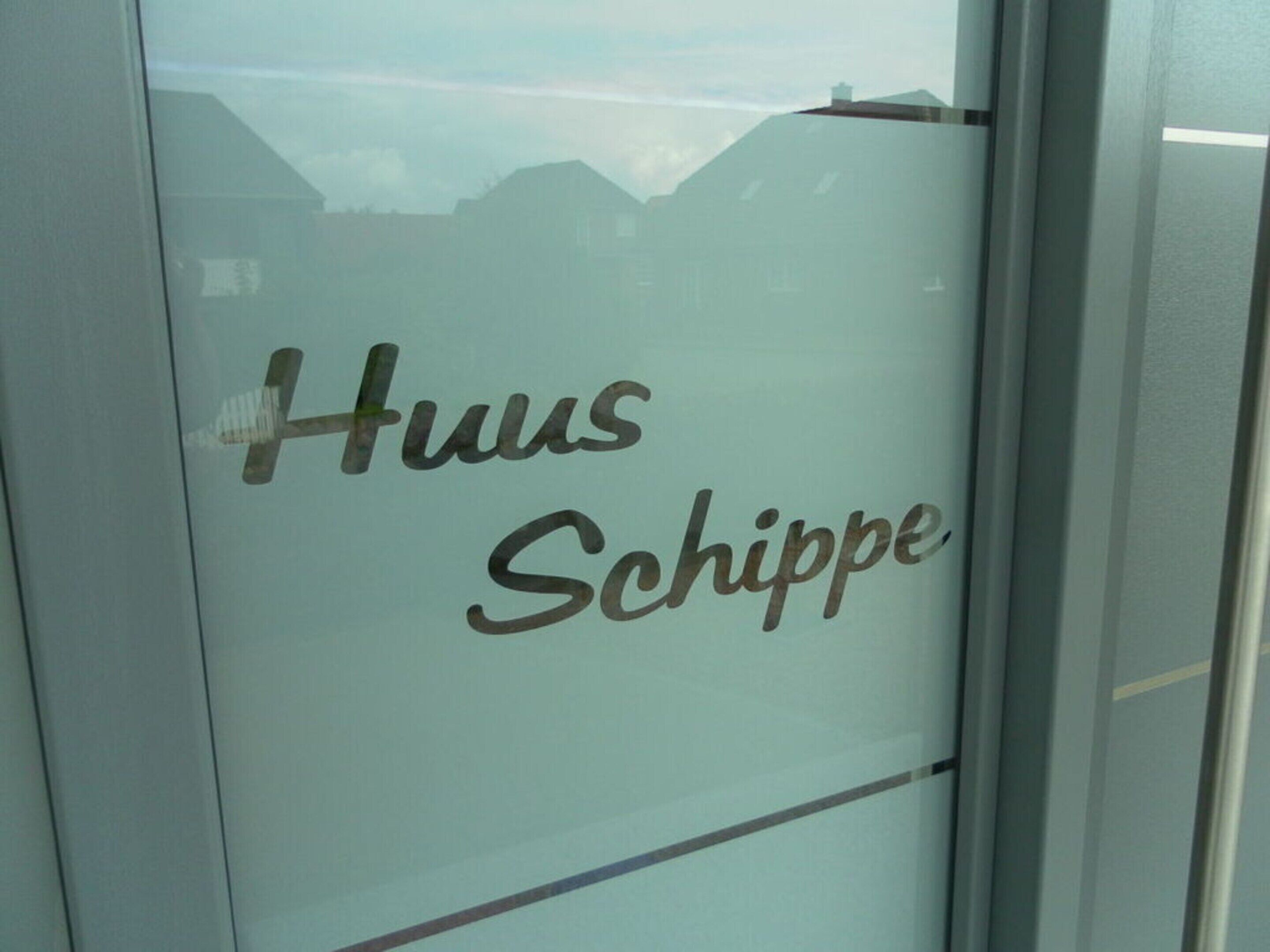 Une porte en verre sur laquelle est inscrit le texte « Haus Schippe ».