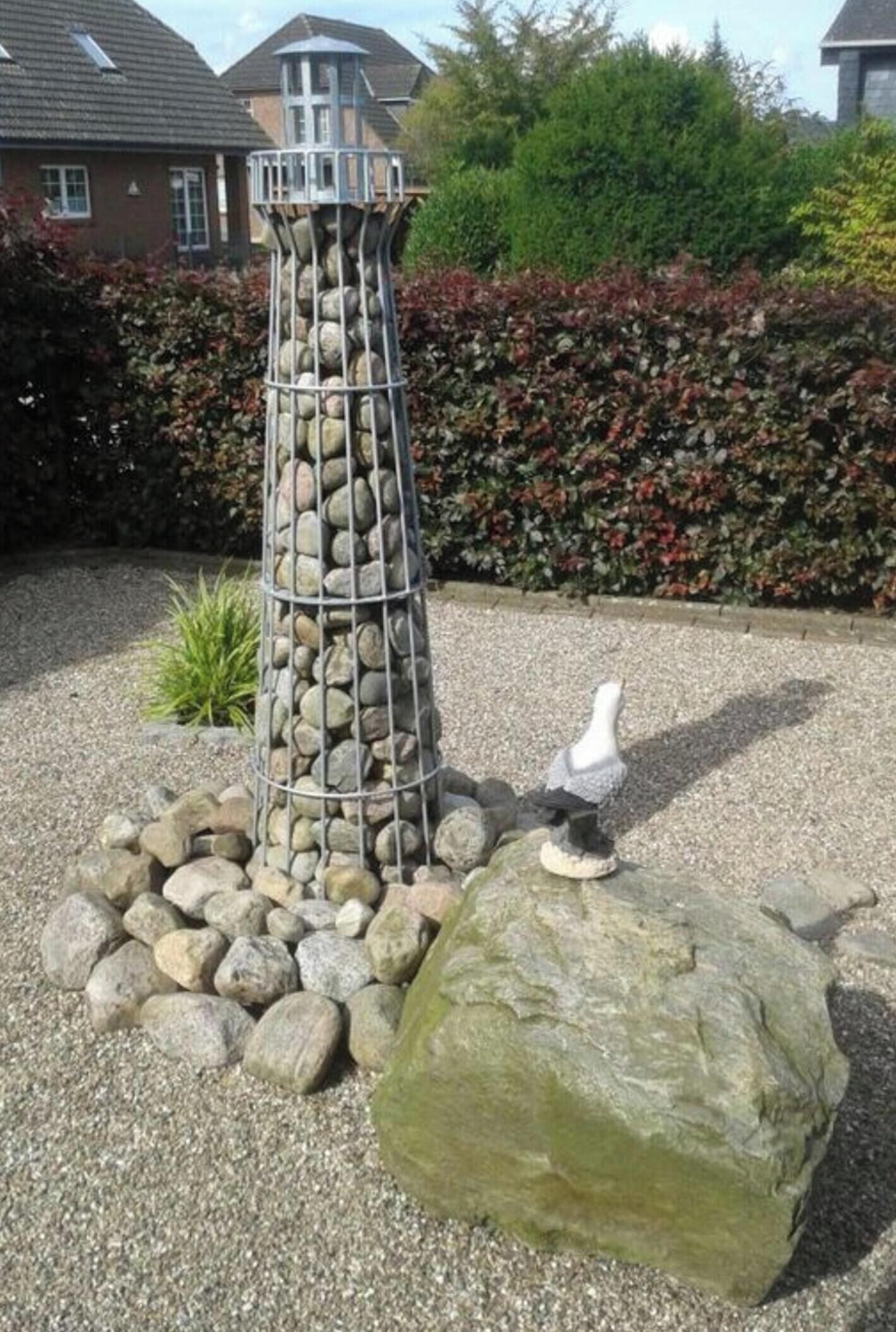 A garden with a stone structure, a large rock, and a bird statue.