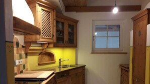 Eine Küche mit Holzschränken, einer Edelstahl-Spüle und einem Fenster über der Arbeitsplatte.