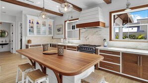 Une cuisine moderne avec un îlot central en bois, des meubles blancs et une grande fenêtre.