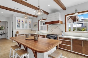Una cocina moderna con una isla de madera, armarios blancos y un ventanal grande.