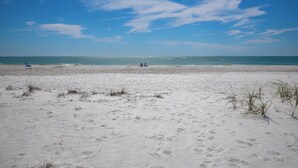 Une plage de sable blanc, un ciel bleu azur et l’océan.