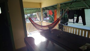 Un'amaca su un tavolo di legno, un balcone con ringhiera e vestiti stesi.
