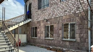 A building with a brick facade, a staircase leading to an upper level, and a tiled patio area.