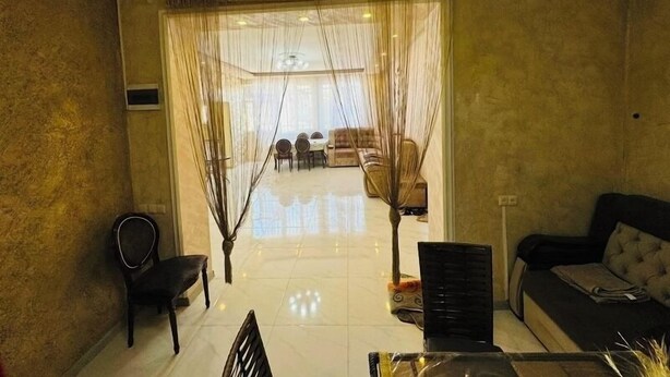 A living room with a sofa, a dining table with chairs, and a view into the dining area.