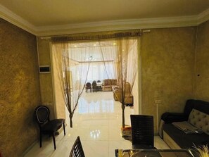 A living room with a sofa, a dining table with chairs, and a view into the dining area. - Cozy Home, remodeled 3bedroom. (Yerevan)