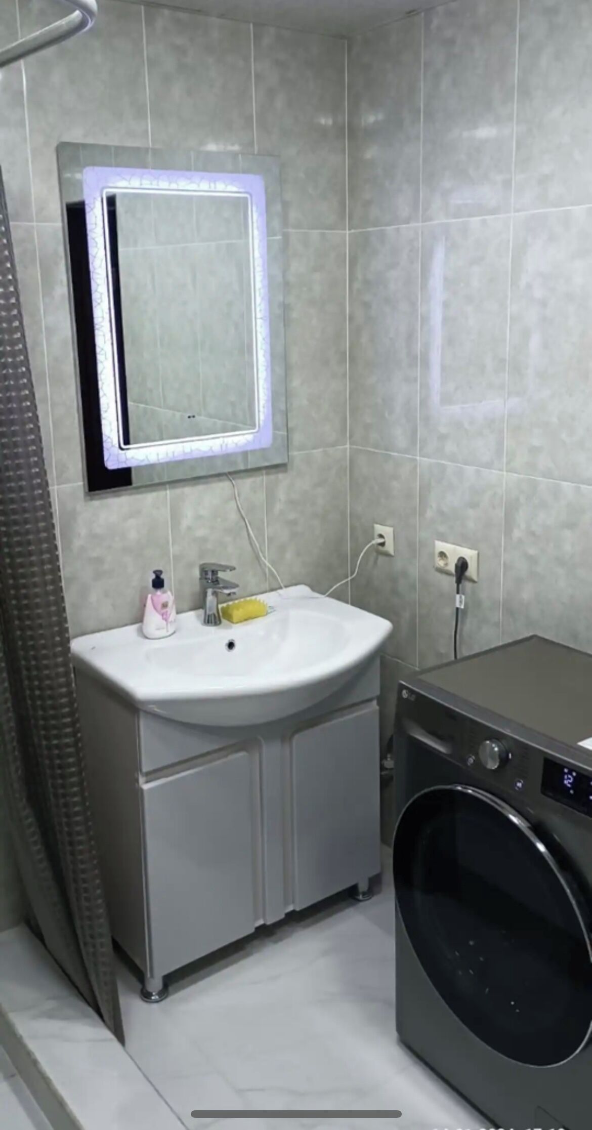 A compact bathroom with a sink, mirror, and washing machine.