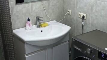 A compact bathroom with a sink, mirror, and washing machine.
