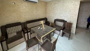 A dining area with a marble table, cushioned sofas, and wicker chairs.