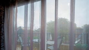 A wooden deck with outdoor furniture, including chairs and tables, and a view of a garden and trees through the window. - Very Nice Manor House in North African Atmosphere (Kortrijk)