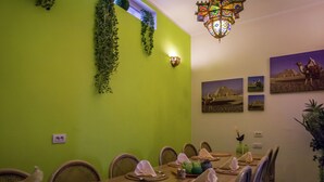 A dining area with a green wall, a chandelier, and desert-themed wall art. - Very Nice Manor House in North African Atmosphere (Kortrijk)